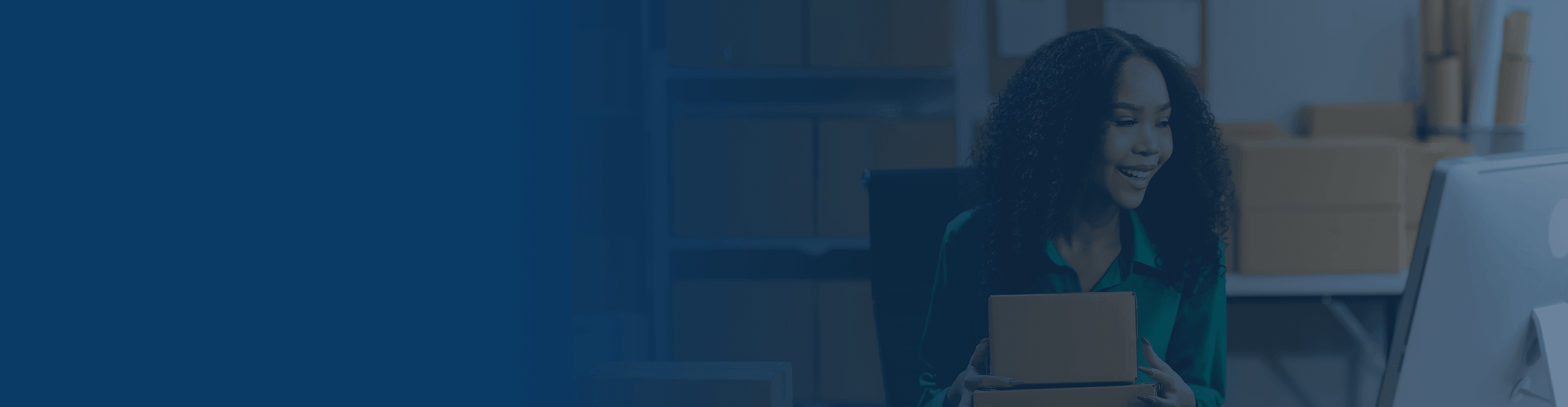 A smiling vendor packing a box on a shelf filled with packages.